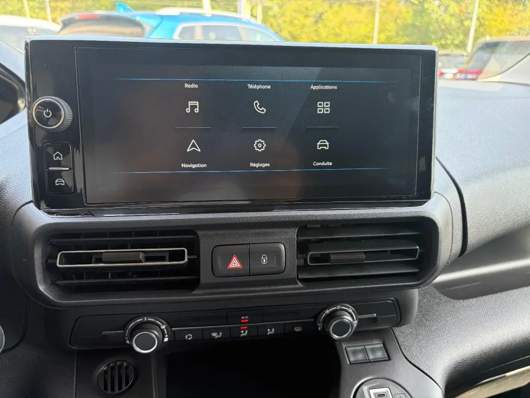 Écran tactile central du tableau de bord du Peugeot Partner 2026 blanc, avec commandes de climatisation et ventilation visibles.