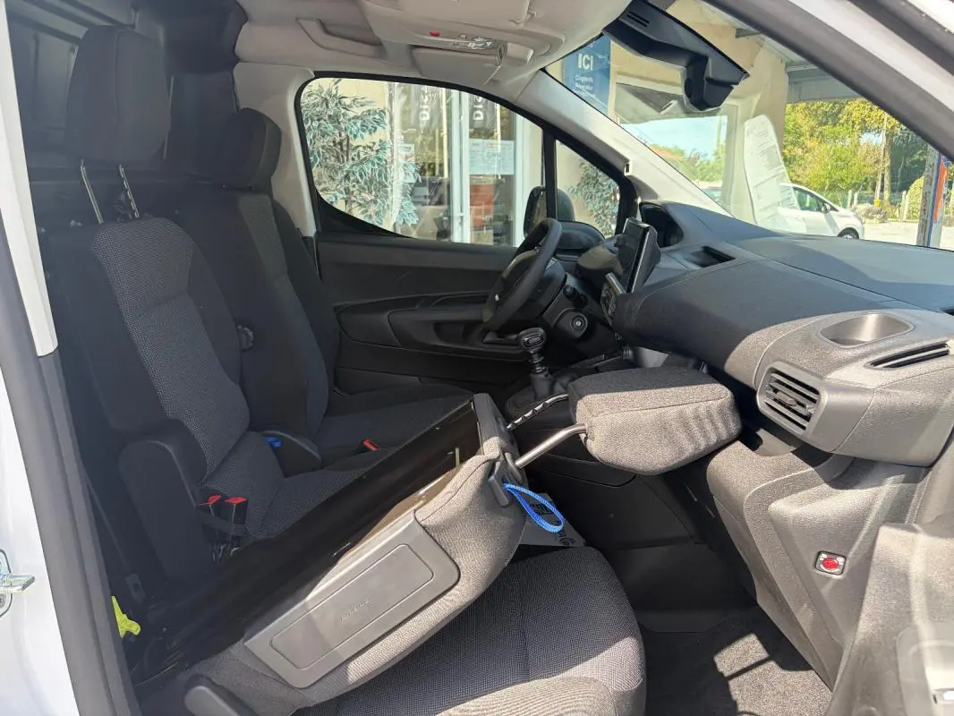 Vue intérieure côté passager du Peugeot Partner blanc 2026, montrant les sièges, le volant multifonctions et l’écran tactile GPS.