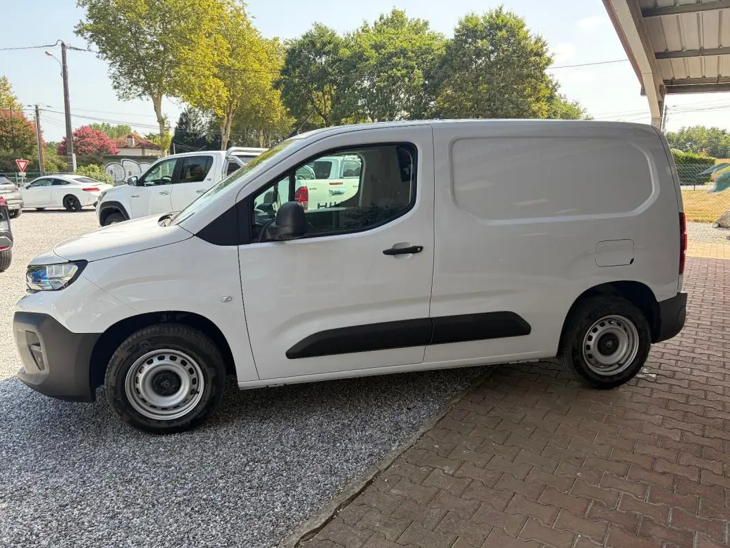 Peugeot Partner blanc vu de profil côté gauche, fourgon utilitaire avec protections noires sur les portières.