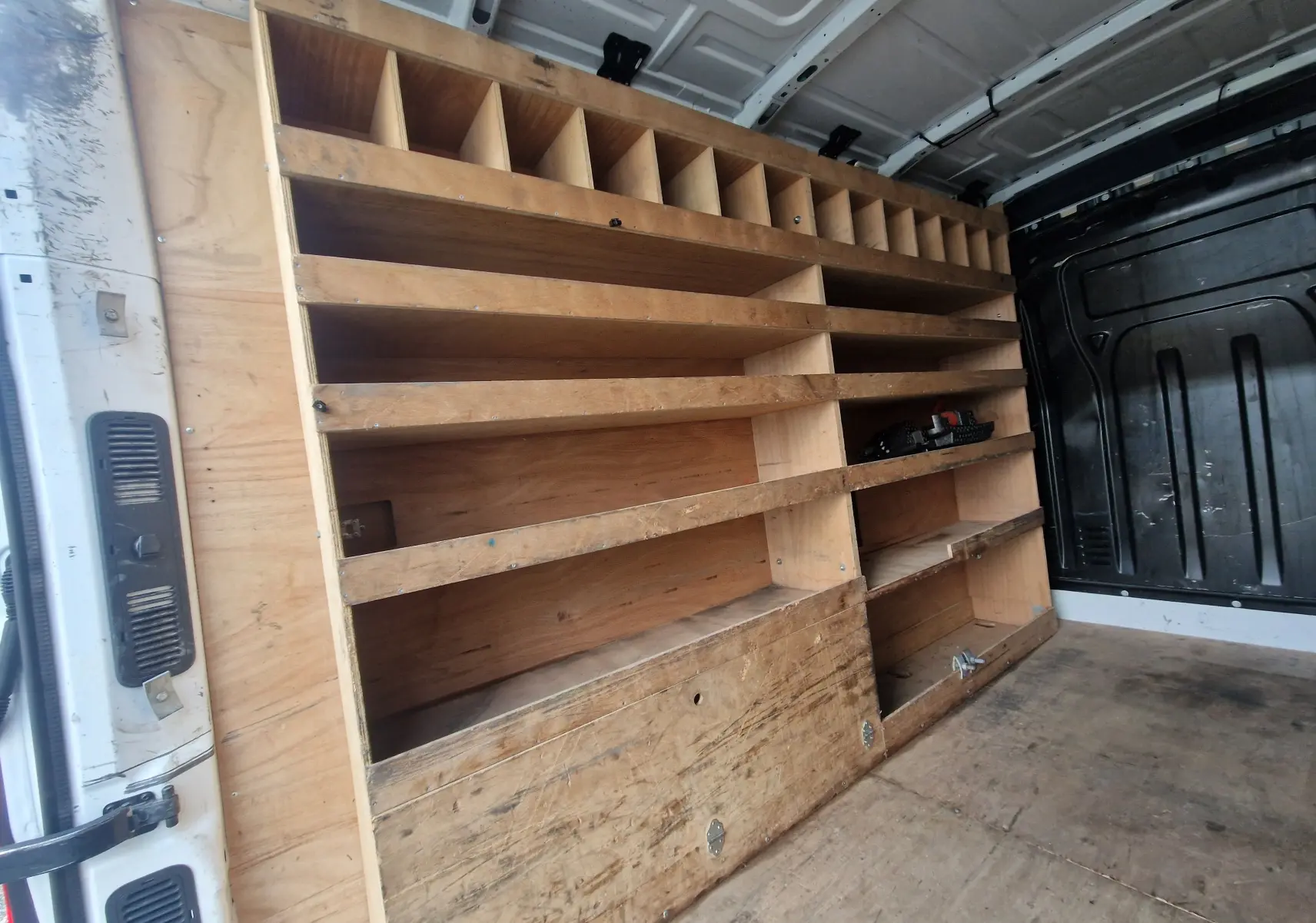 Vue intérieure côté gauche du Renault Master blanc 2020 avec aménagements en bois pour rangement et outils.