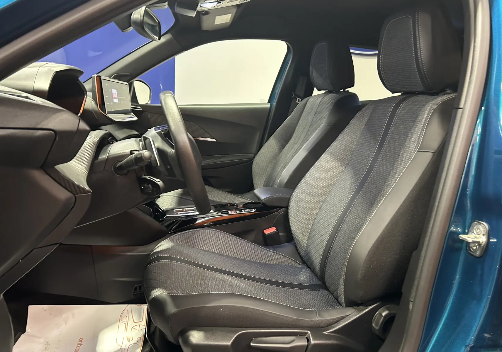Intérieur avant droit du Peugeot 2008 Allure Hybrid 145 bleu Obsession, sièges tissu et tableau de bord moderne avec écran tactile.