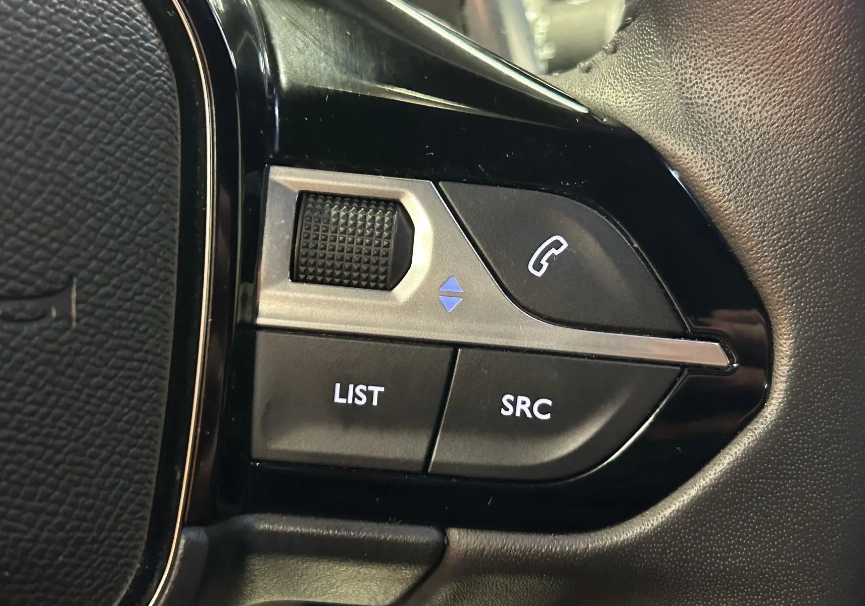 Gros plan sur les commandes de téléphonie et audio au volant du Peugeot 2008 Allure Hybrid 145, finition noire.