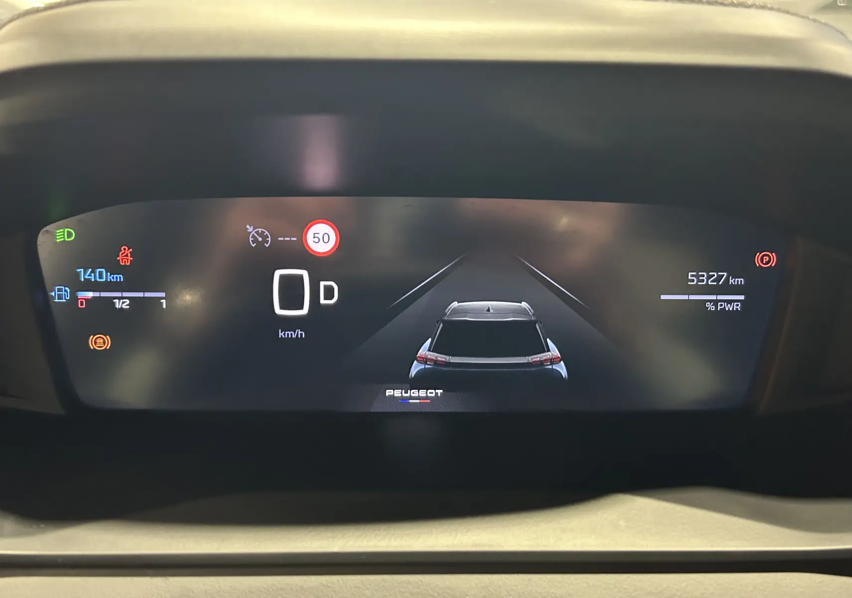 Vue rapprochée du tableau de bord numérique du Peugeot 2008 Allure Hybrid 145, affichant la vitesse, autonomie et aides à la conduite.