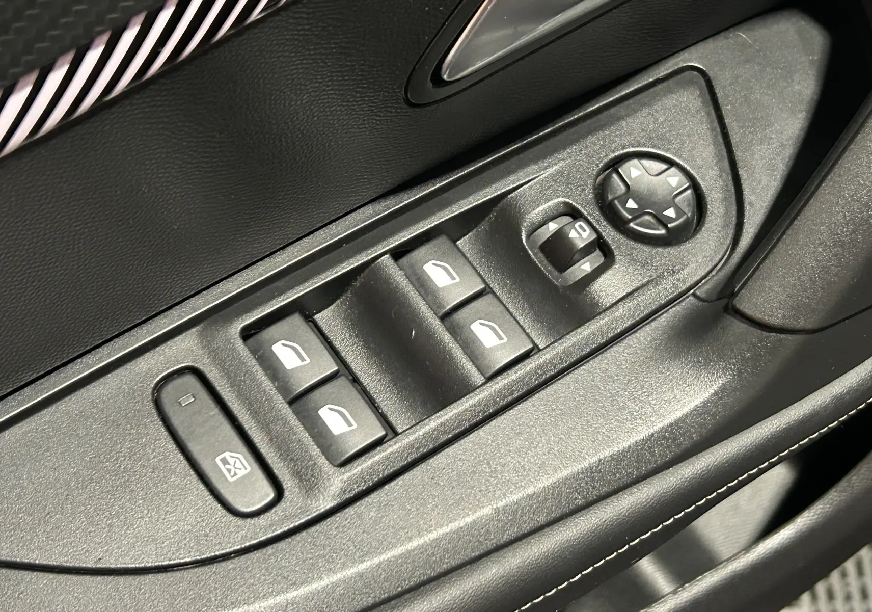 Gros plan sur les commandes de lève-vitres et réglage des rétroviseurs côté conducteur d’un Peugeot 2008 Allure Hybrid 2025.