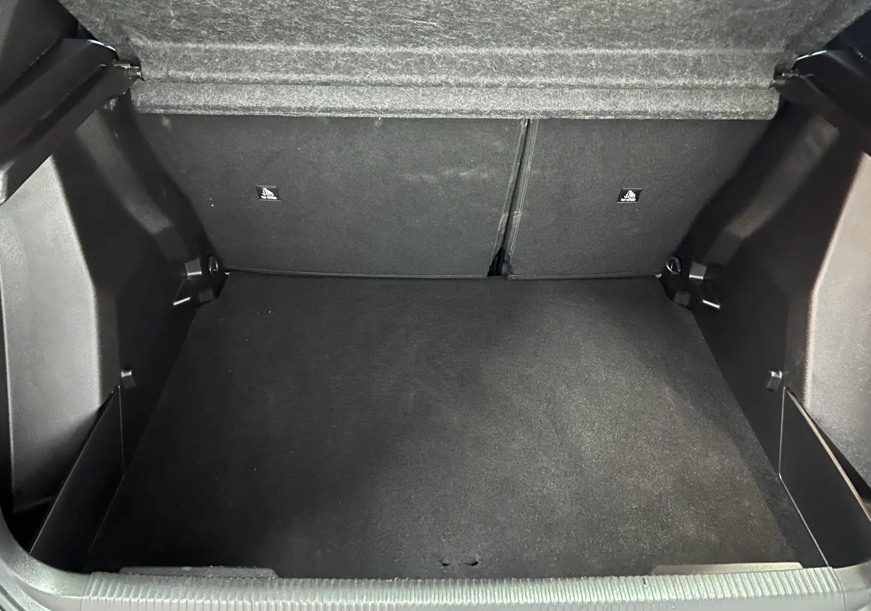 Coffre vide de Peugeot 2008 Allure Hybrid 145 en vue intérieure, montrant l'espace de chargement en tissu noir.