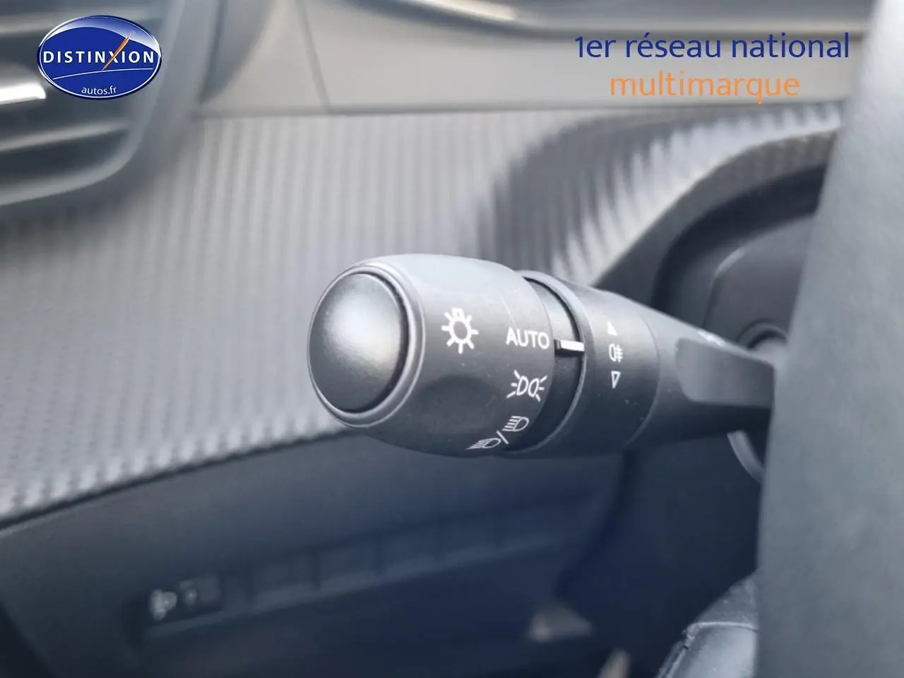 Gros plan sur la commande des phares automatique dans l’habitacle gris d’une Peugeot 208 1.2 PureTech 100 Allure 2024.