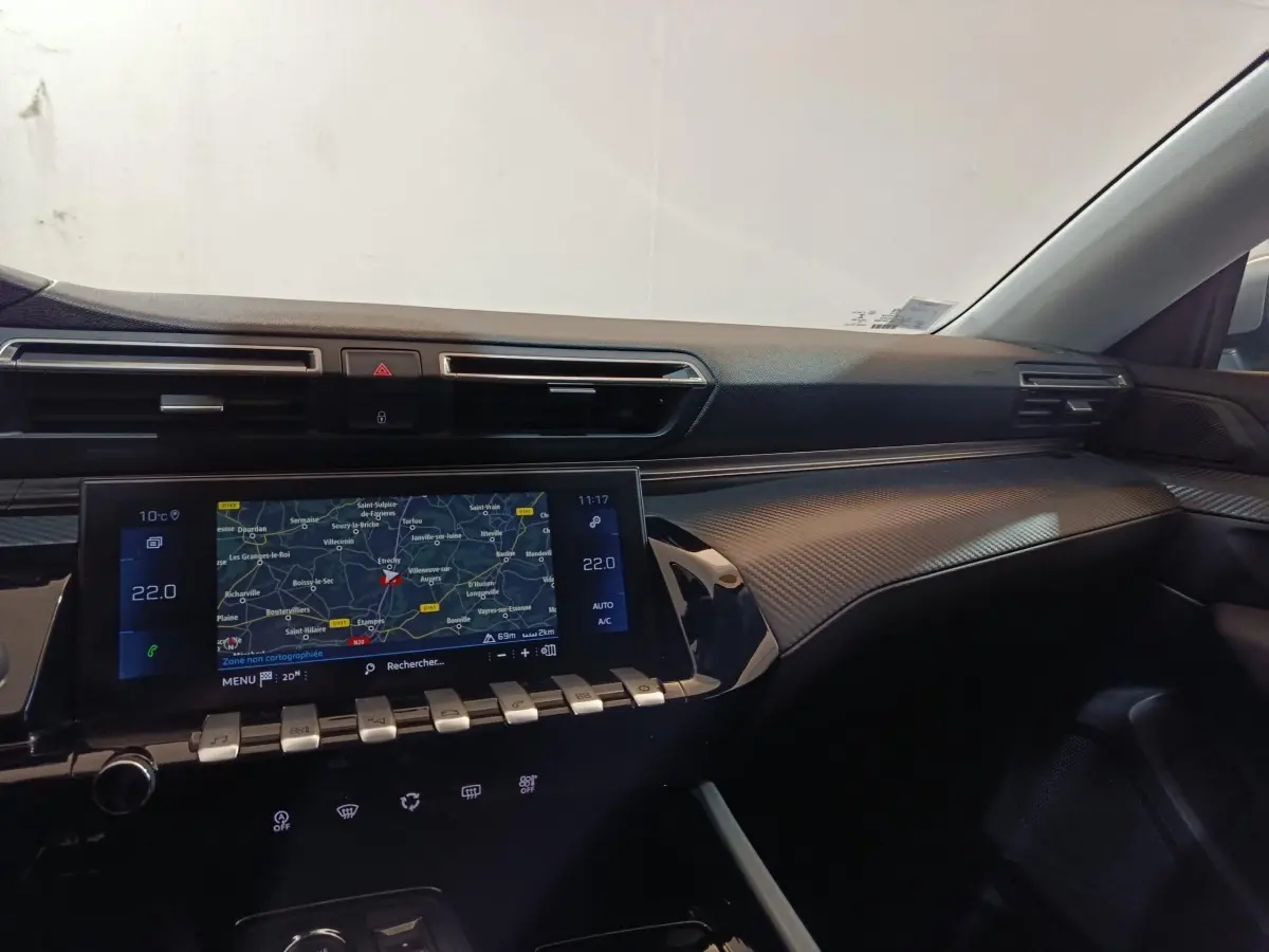 Vue intérieure côté passager du tableau de bord noir avec écran tactile de navigation et finition carbone du Peugeot 508 gris clair.