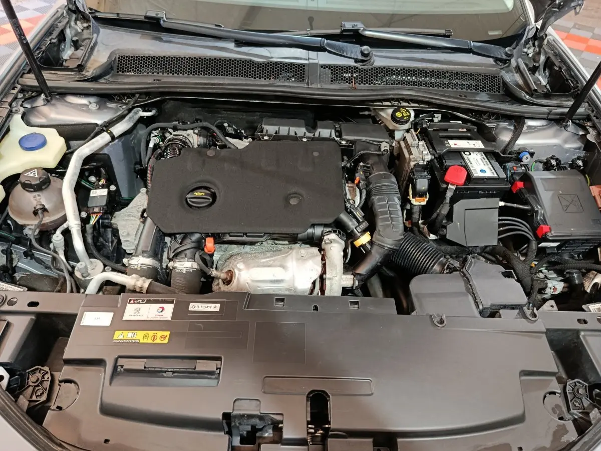 Vue rapprochée du compartiment moteur du Peugeot 508 BlueHDi 130 gris clair avec capot ouvert, montrant les composants diesel.