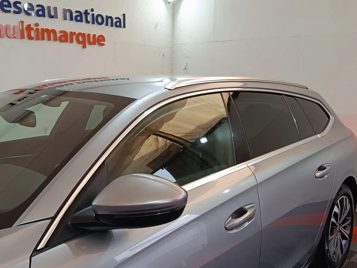 Vue latérale gauche rapprochée d’une Peugeot 508 gris clair avec rétroviseur et vitres teintées.
