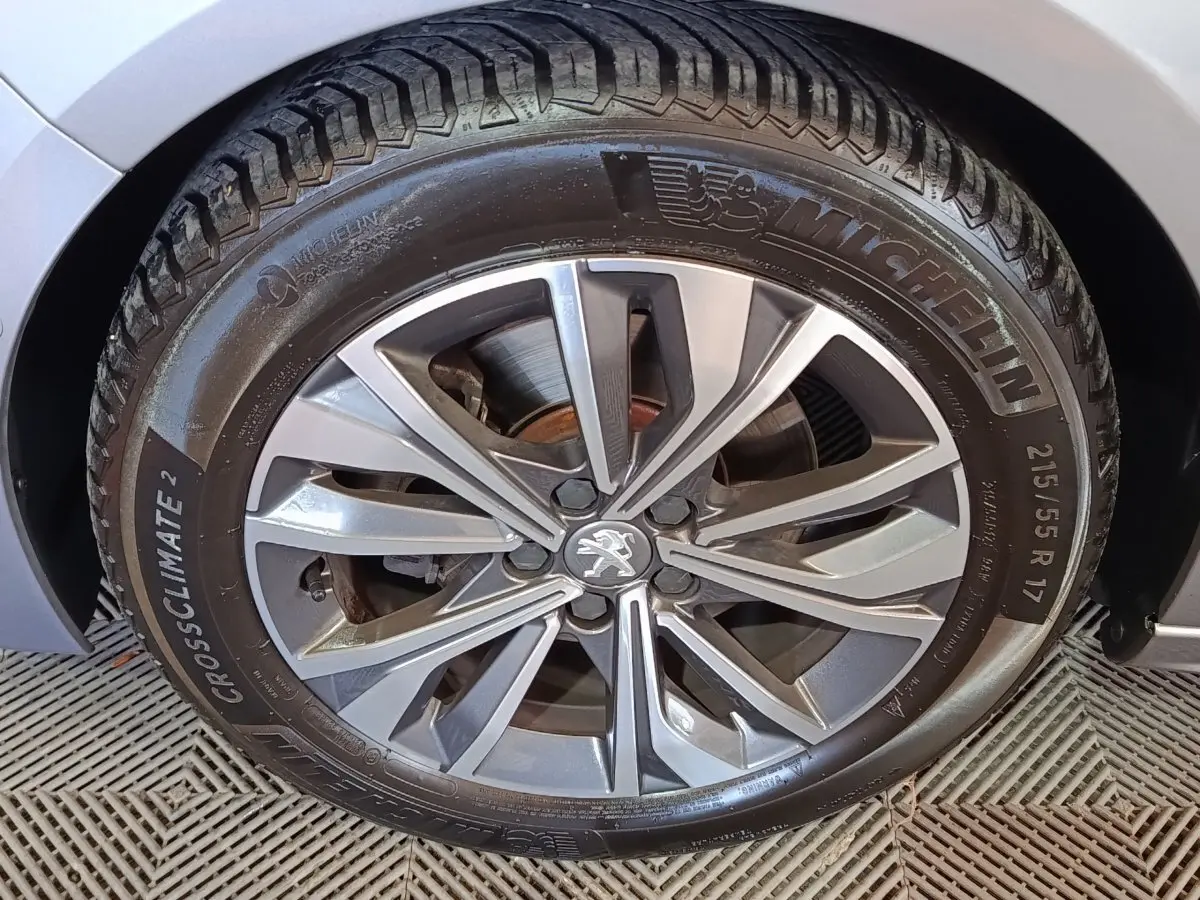 Gros plan sur la roue avant droite gris clair de la Peugeot 508 avec jante alliage et pneu Michelin CrossClimate 2.