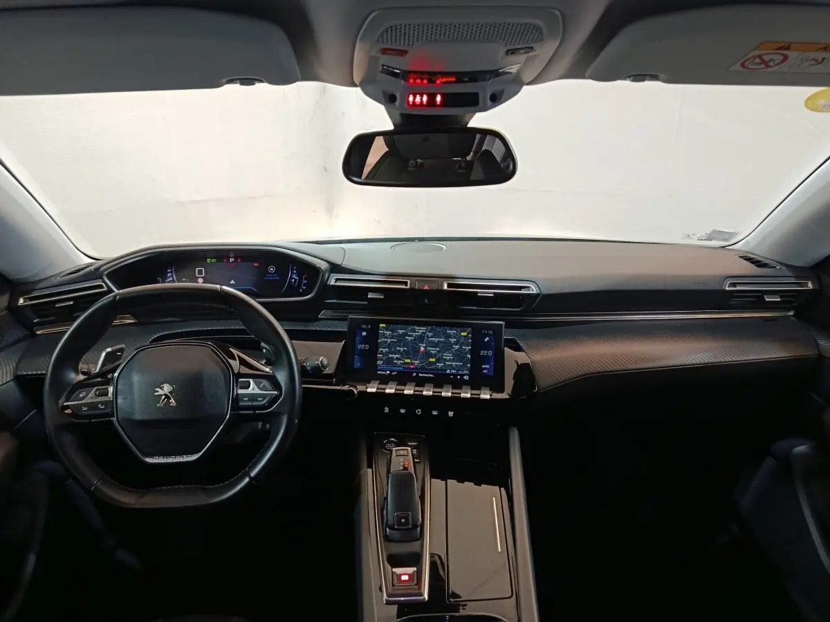 Vue intérieure avant du tableau de bord noir et volant cuir de la Peugeot 508 gris clair avec écran tactile central et affichage numérique.