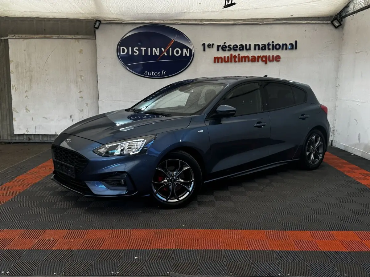 Ford Focus 5 portes bleu en 3/4 avant droit, jantes alliage noires et calandre noire distinctive St-Line.