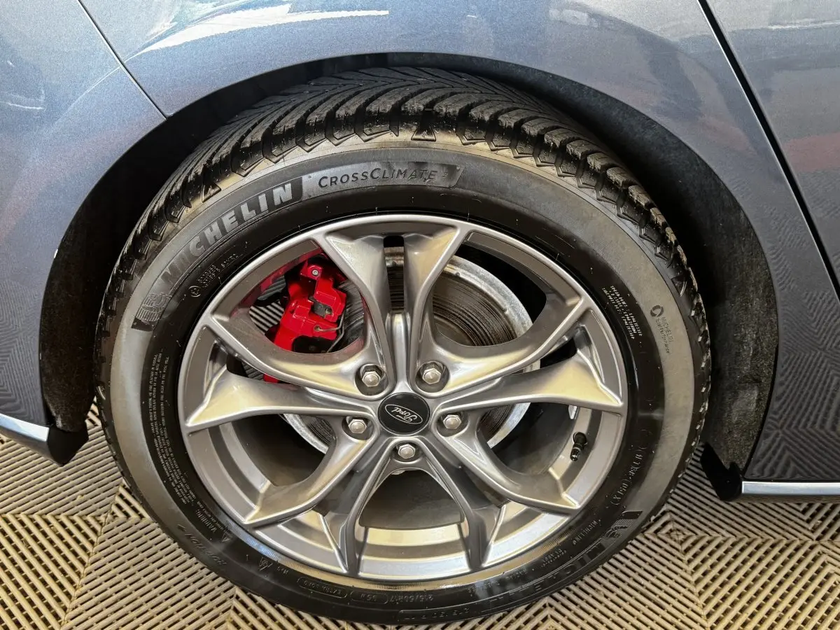 Gros plan sur la roue arrière droite d’une Ford Focus bleu 2022 avec étrier de frein rouge et jante alliage.