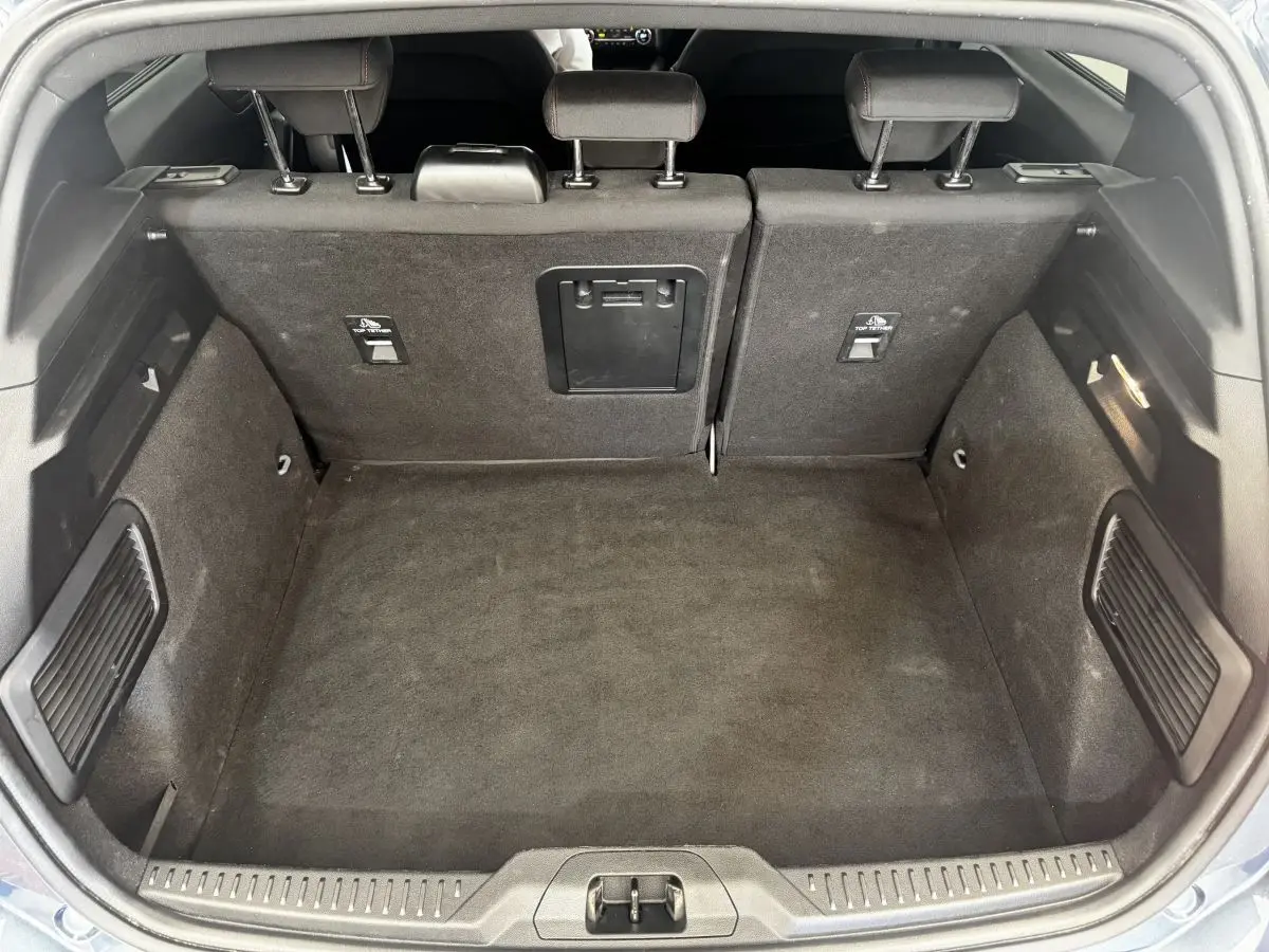 Coffre ouvert vu de l'arrière d'une Ford Focus 5 portes bleu, banquette arrière rabattable 2/3-1/3 visible.