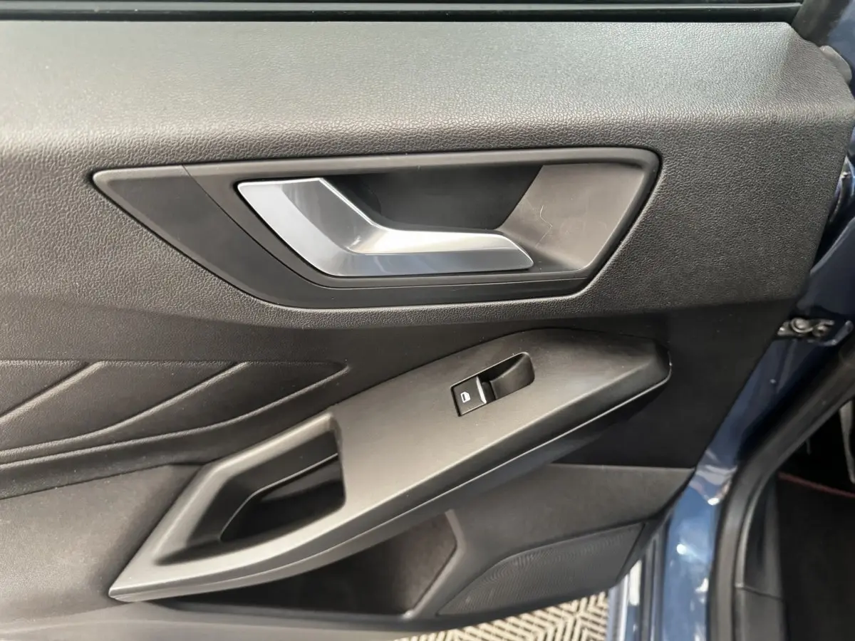 Vue rapprochée de la porte avant gauche bleu foncé de la Ford Focus 5P avec poignée argentée et commande de vitre.
