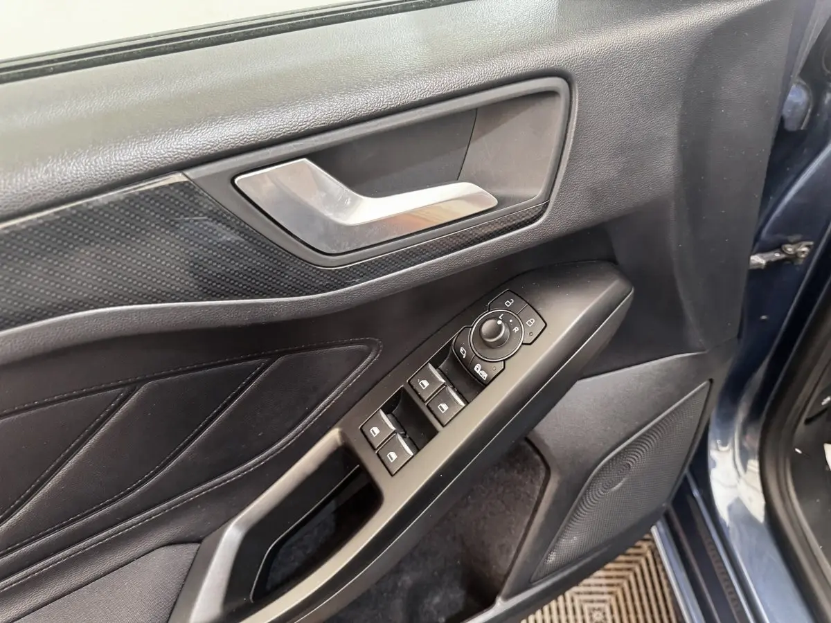 Vue rapprochée de la porte avant gauche bleu foncé de la Ford Focus avec commandes électriques des vitres et rétroviseurs.