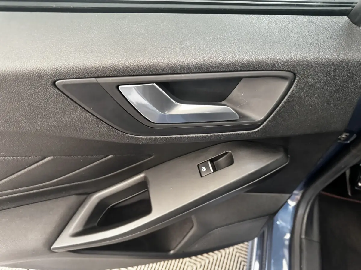 Gros plan sur la poignée intérieure et la commande de vitre côté gauche d’une Ford Focus bleu 5 portes 2022.