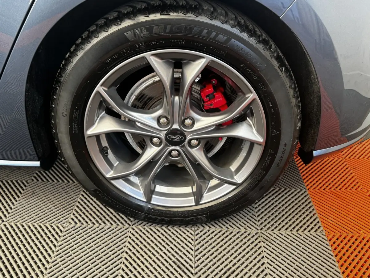 Gros plan sur la roue avant droite d'une Ford Focus bleu 2022, avec jante alliage et étrier de frein rouge visible.