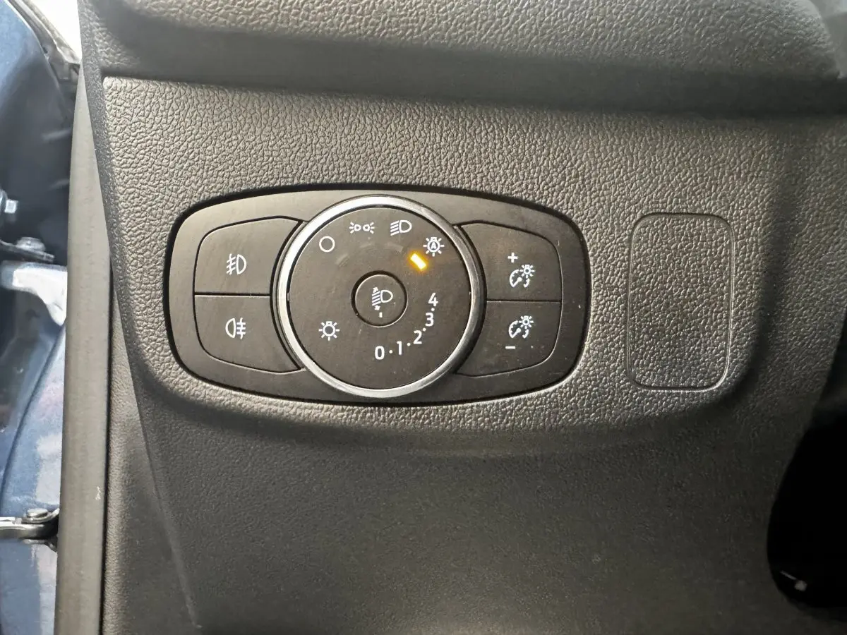 Gros plan sur le panneau de commande des phares à gauche du tableau de bord d’une Ford Focus bleu 5 portes 2022.