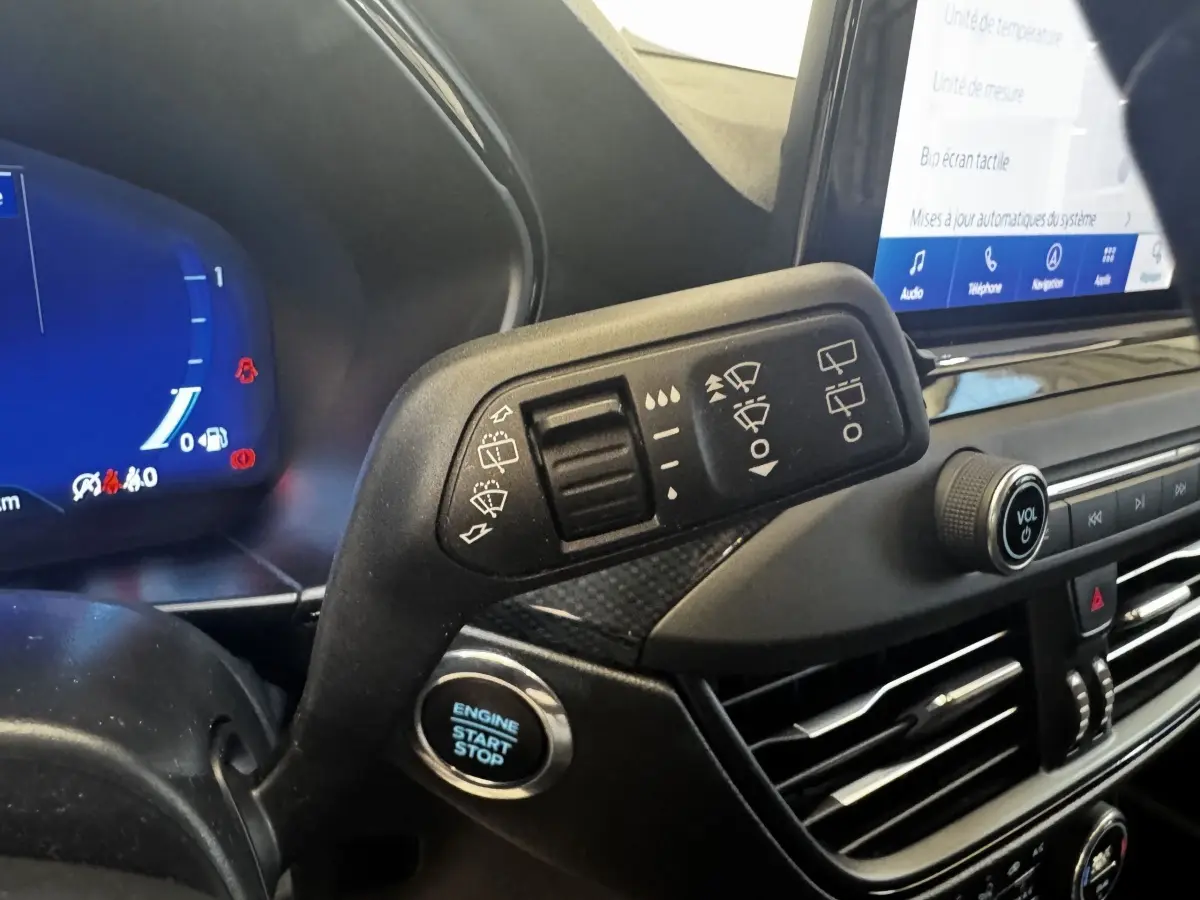 Gros plan sur la commande d'essuie-glace et le bouton start/stop dans l'habitacle de la Ford Focus bleu 2022.