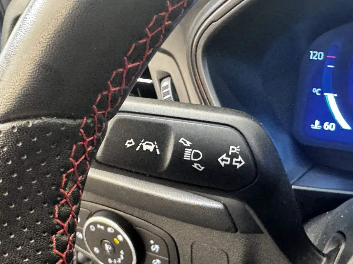 Gros plan sur le volant avec surpiqûres rouges et commandes d’aide à la conduite de la Ford Focus 2022.