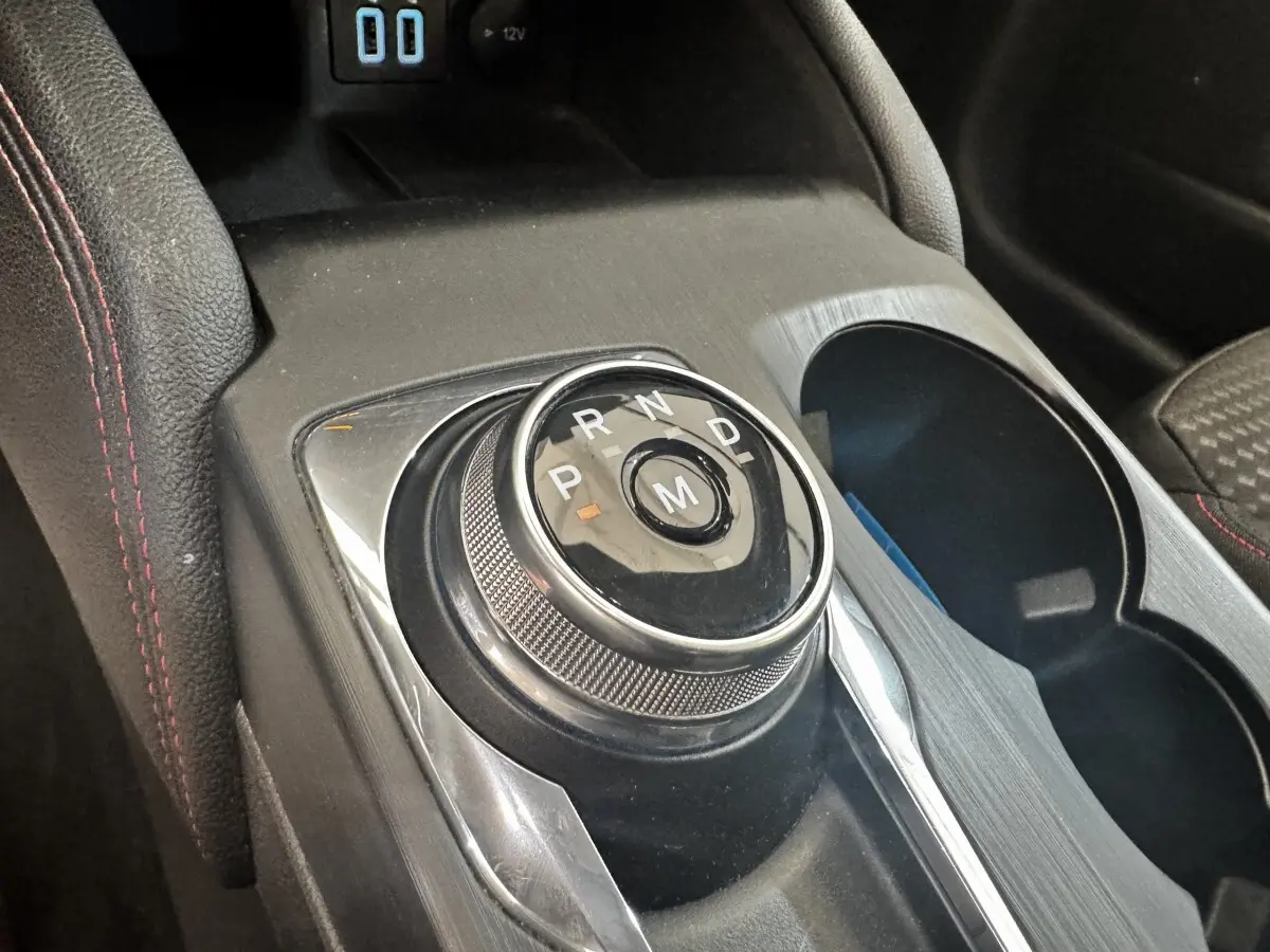 Gros plan sur la molette de boîte automatique noire et chrome au centre de la console d'une Ford Focus bleu St-Line.