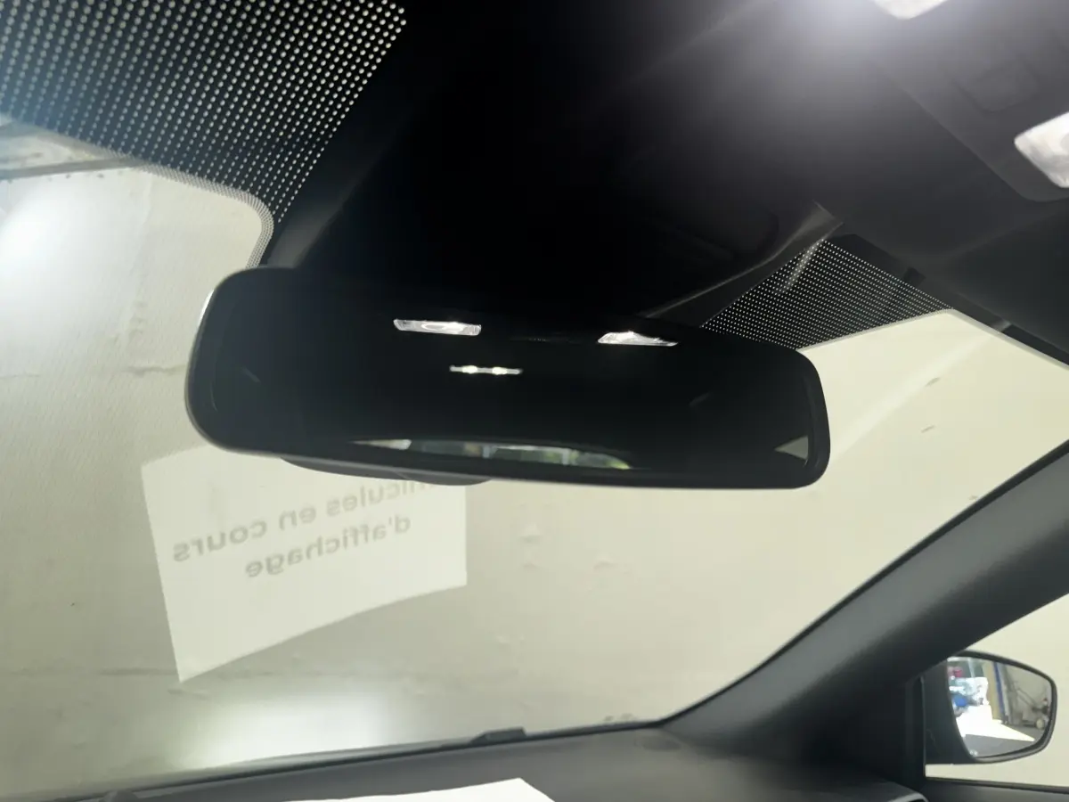 Vue intérieure centrée sur le rétroviseur intérieur d'une Ford Focus bleue, avec partie du pare-brise et rétroviseur latéral droit visible.