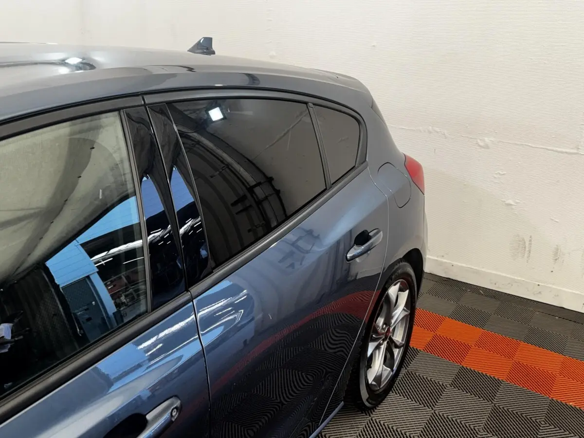 Vue côté droit arrière d'une Ford Focus 5 portes bleu métallisé avec vitres teintées et jantes alliage sport.