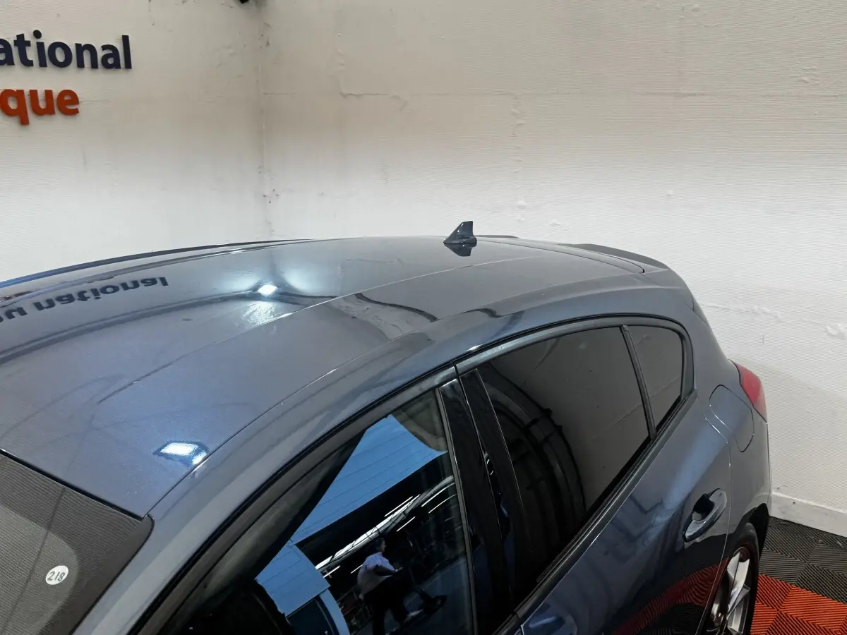 Vue 3/4 arrière droite d'une Ford Focus 5 portes bleu métallisé avec vitres teintées en intérieur showroom.