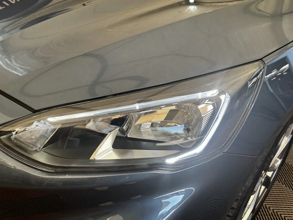 Gros plan sur le phare avant droit de la Ford Focus 5P bleu métallisé, soulignant ses détails LED modernes.