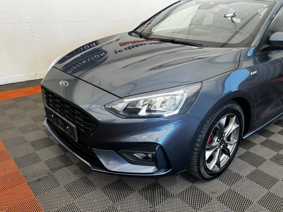 Vue 3/4 avant droit d'une Ford Focus St-Line bleue avec phares LED et jantes alliage sport visibles.