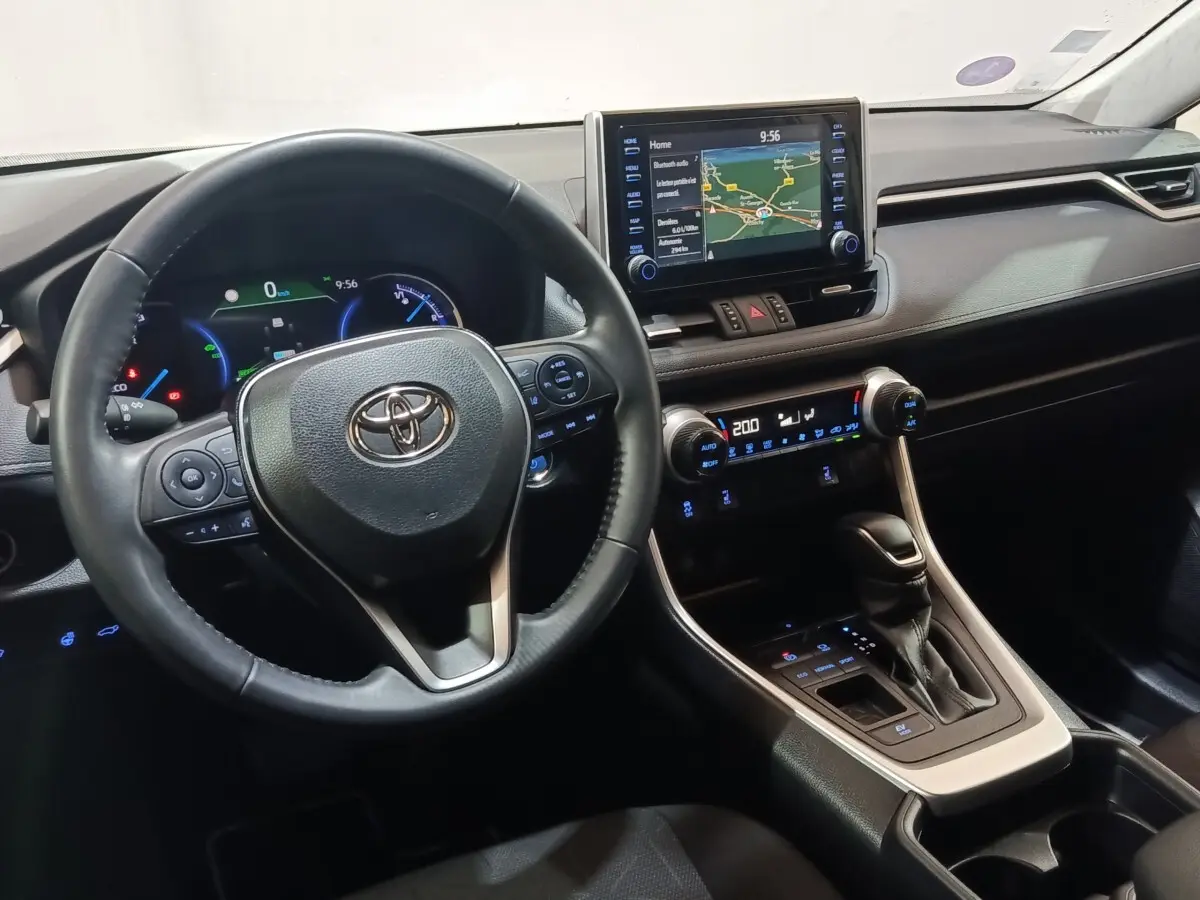 Vue intérieure du tableau de bord et volant du Toyota RAV4 Hybride 2WD 218ch avec écran tactile central et commandes au volant.