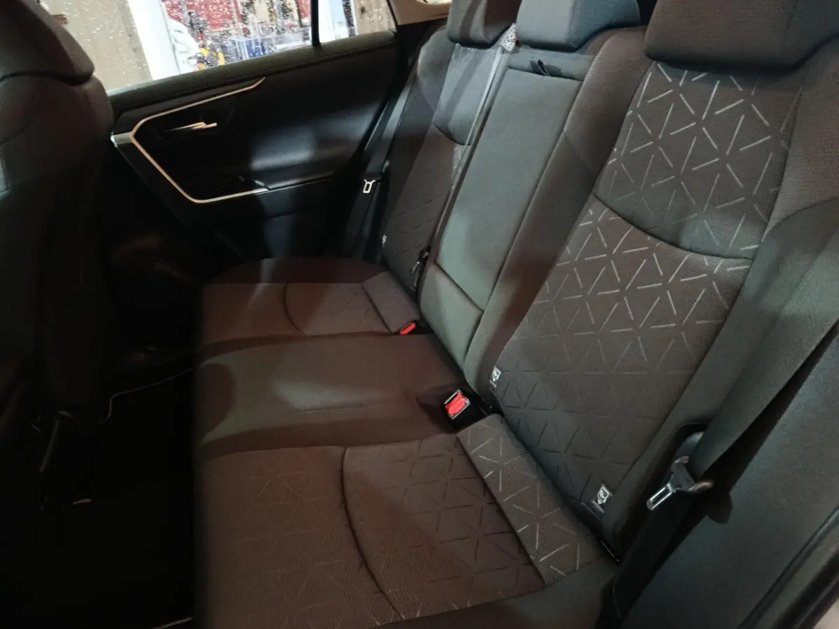 Vue latérale intérieure montrant la banquette arrière noire du Toyota RAV4 Hybride 2WD 2021 avec motifs géométriques.