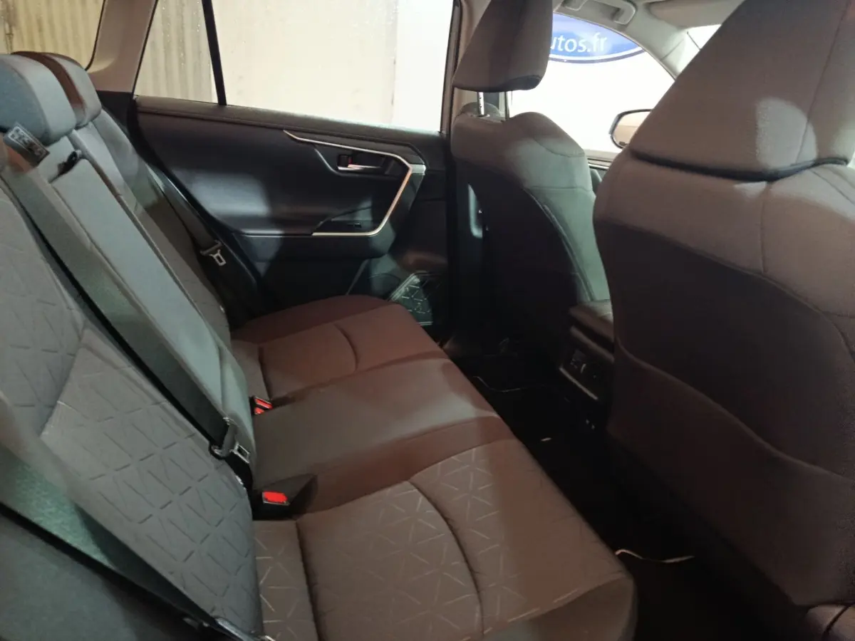 Vue intérieure montrant la banquette arrière grise du Toyota RAV4 hybride 2021, avec ceintures de sécurité et portes latérales.