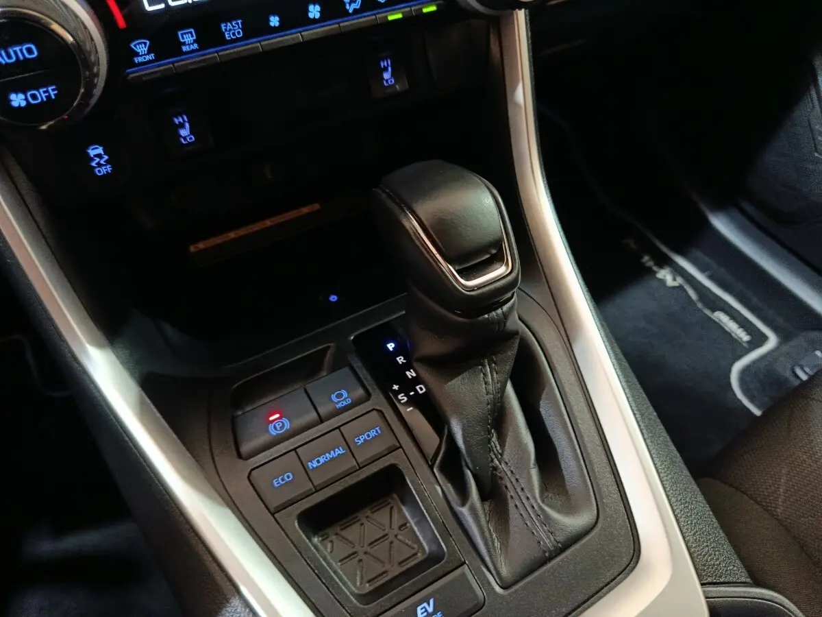 Gros plan sur la console centrale du Toyota RAV4 hybride 2021, montrant levier de vitesses et boutons modes de conduite.