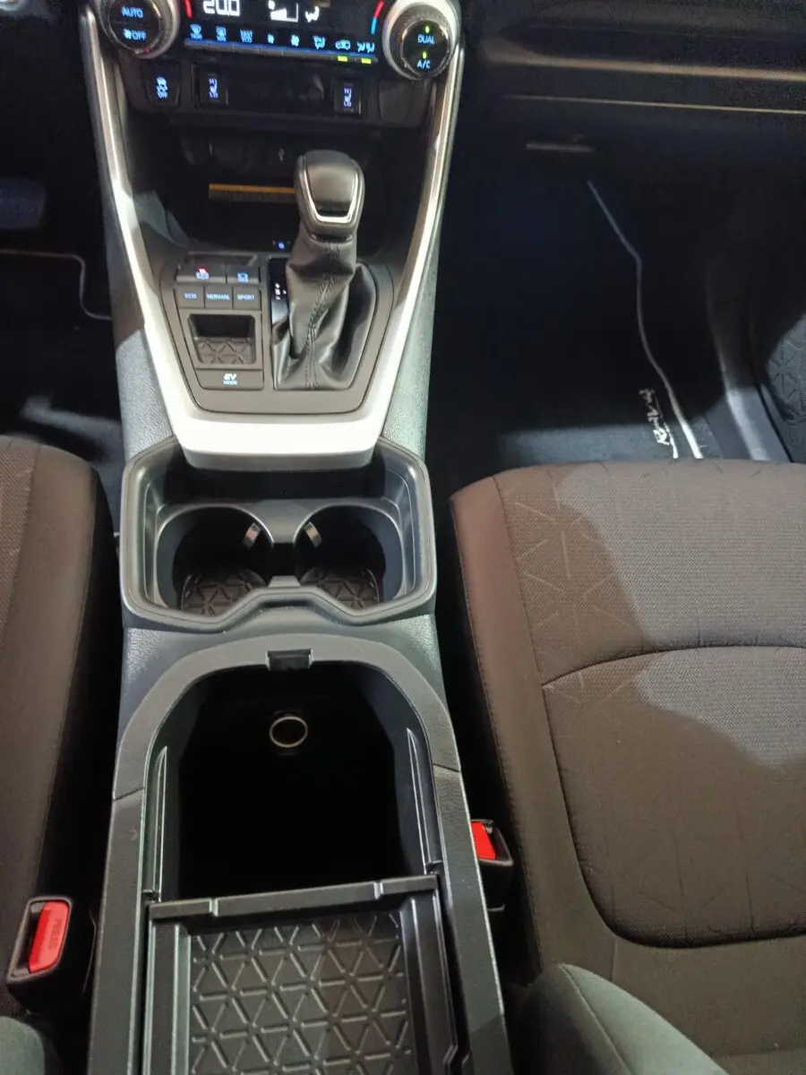 Vue intérieure centrée sur la console centrale noire avec levier de vitesse et sièges tissu marron foncé du Toyota RAV4.