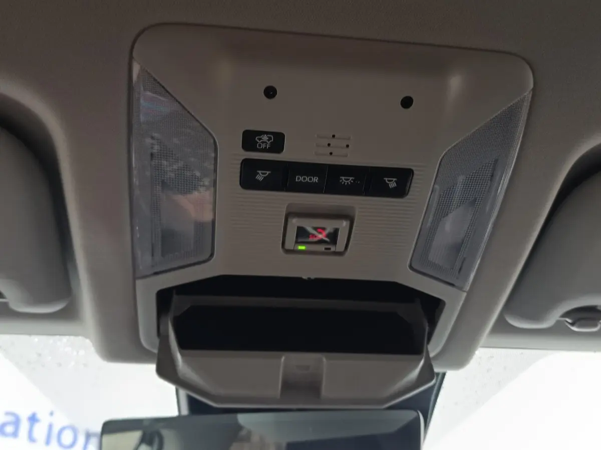 Vue en contre-plongée du plafonnier gris clair du Toyota RAV4 Hybride 2021 avec commandes d’éclairage et compartiment ouvert.