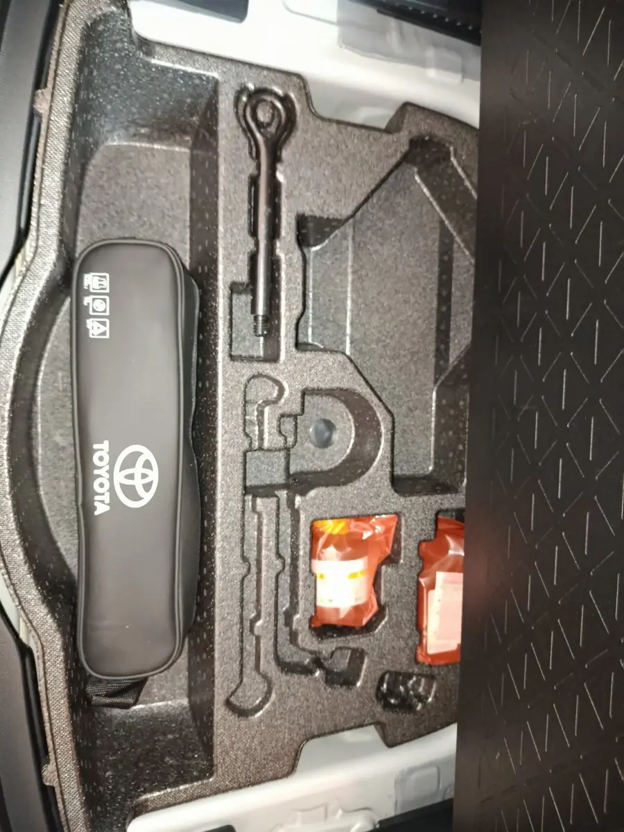 Vue rapprochée de la trousse à outils et accessoires dans le coffre du Toyota RAV4 hybride 2021, rangement en mousse noire.