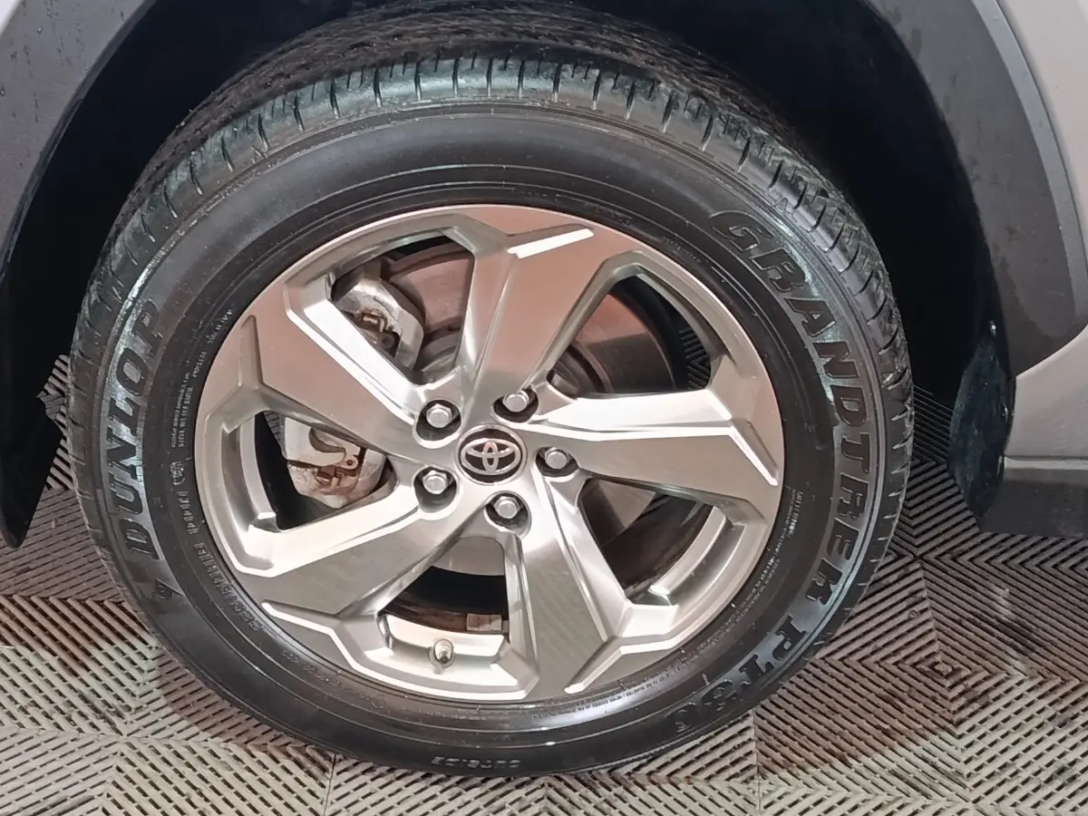 Gros plan sur la roue avant droite du Toyota RAV4 hybride, jante alliage argentée avec logo Toyota au centre.