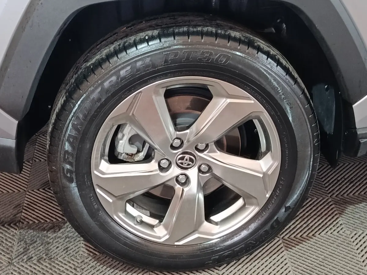 Gros plan sur la roue avant droite du Toyota RAV4 hybride 2021, jante alliage argentée et pneu Dunlop noir.