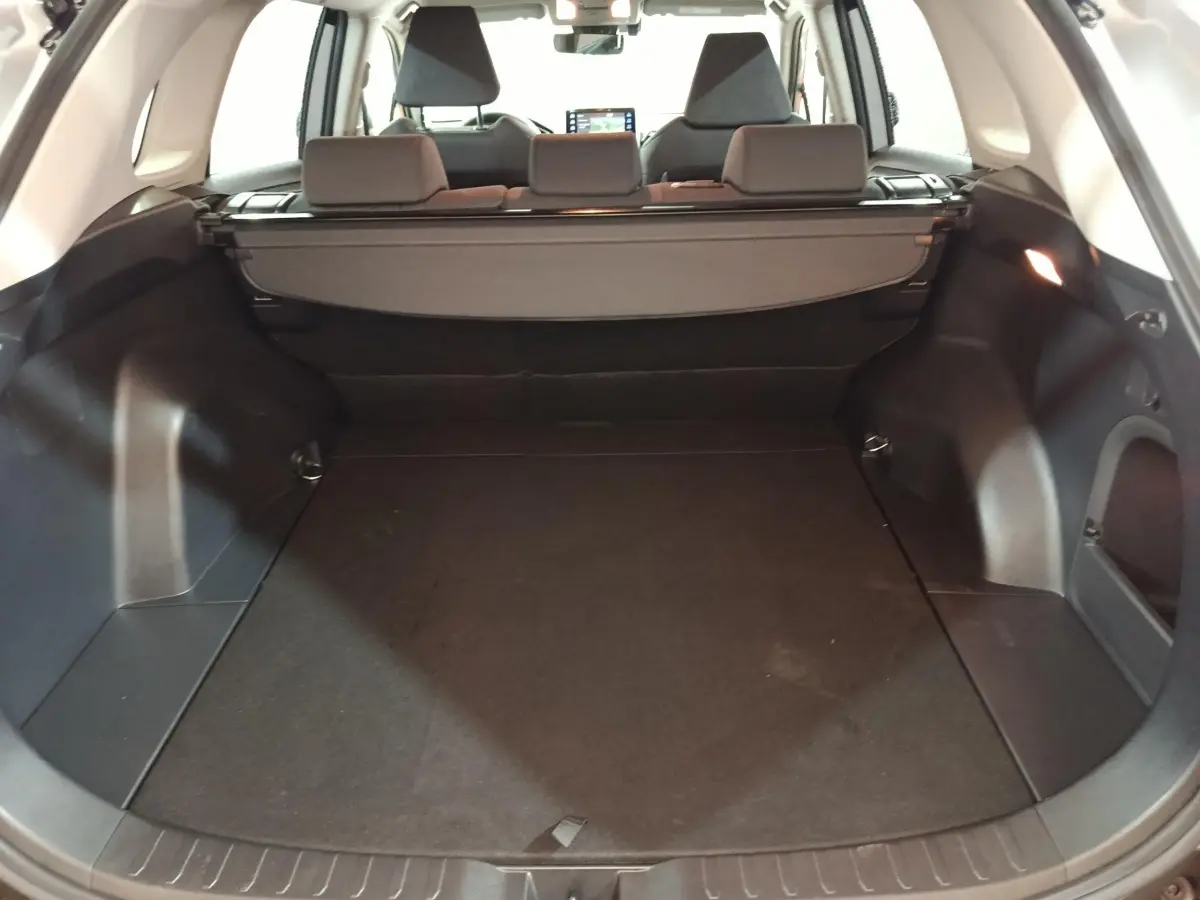 Coffre ouvert du Toyota RAV4 hybride 2WD 2021, vue arrière, intérieur noir avec cache-bagages déployé.
