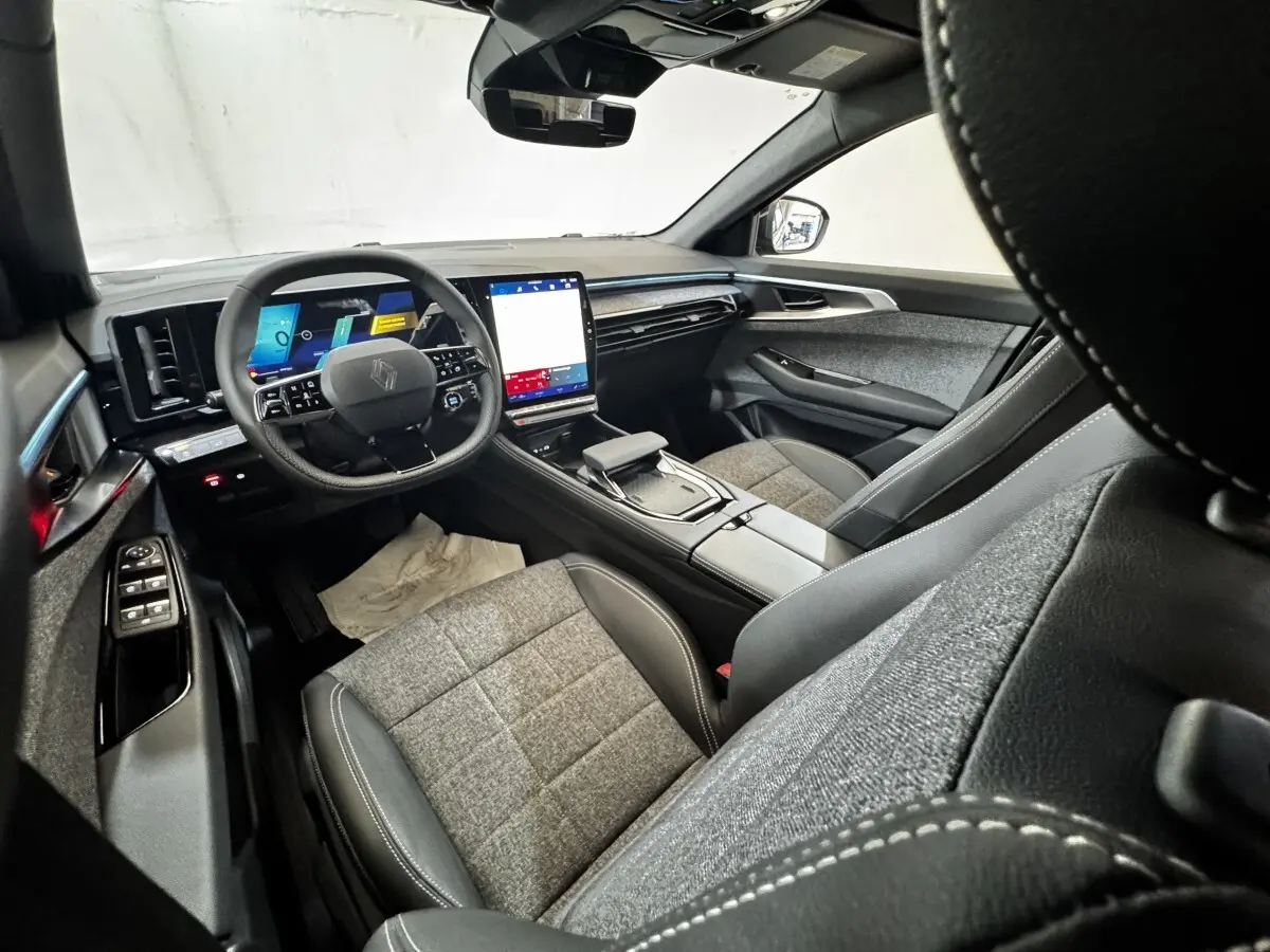Intérieur Renault Espace 2025 vu côté conducteur, tableau de bord moderne avec écran tactile vertical et sièges tissu-cuir gris.
