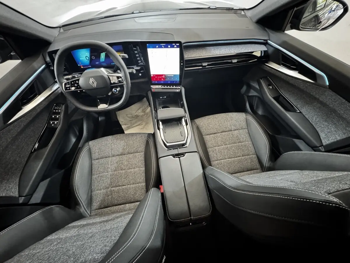 Vue intérieure avant du Renault Espace 2025 noir, tableau de bord moderne avec grand écran tactile vertical et volant multifonctions.