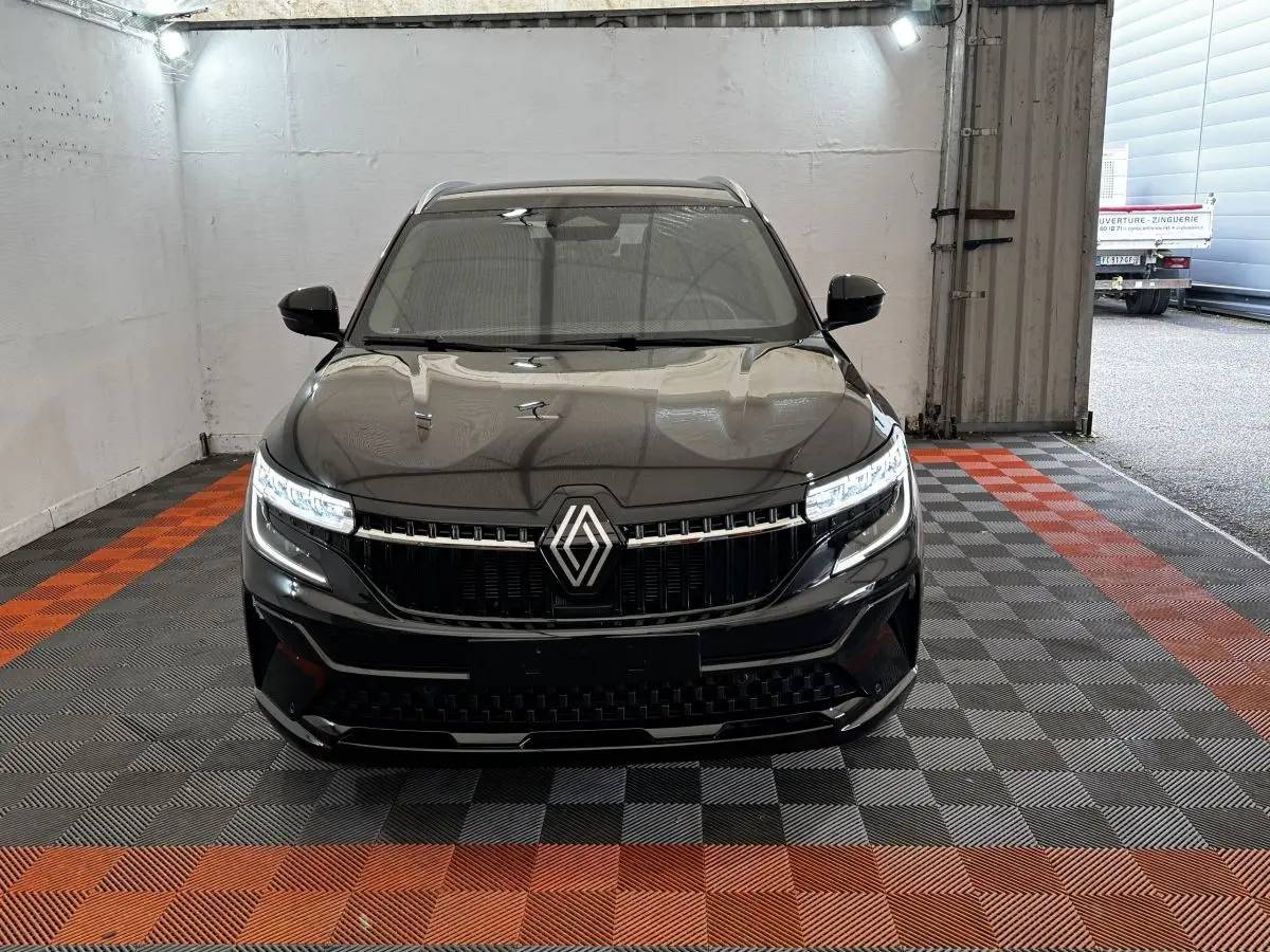 Vue frontale du Renault Espace noir 2025 avec calandre marquée et phares LED allumés dans un garage.