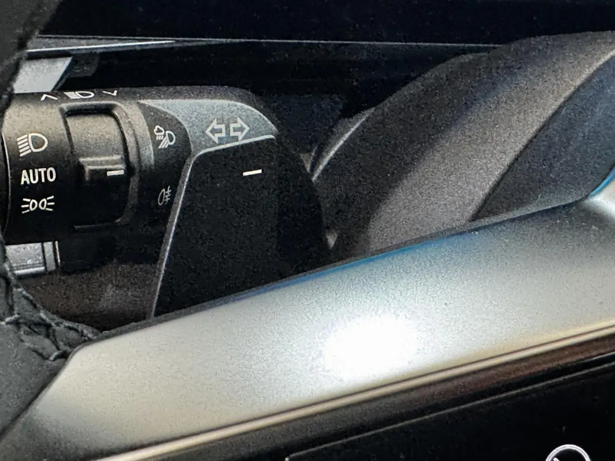 Gros plan sur la commande des feux et clignotants à gauche du volant d'un Renault Espace noir 2025.