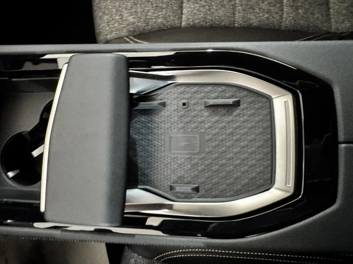 Vue plongeante sur la console centrale noire du Renault Espace 2025 avec zone de recharge sans fil et accoudoir rembourré.