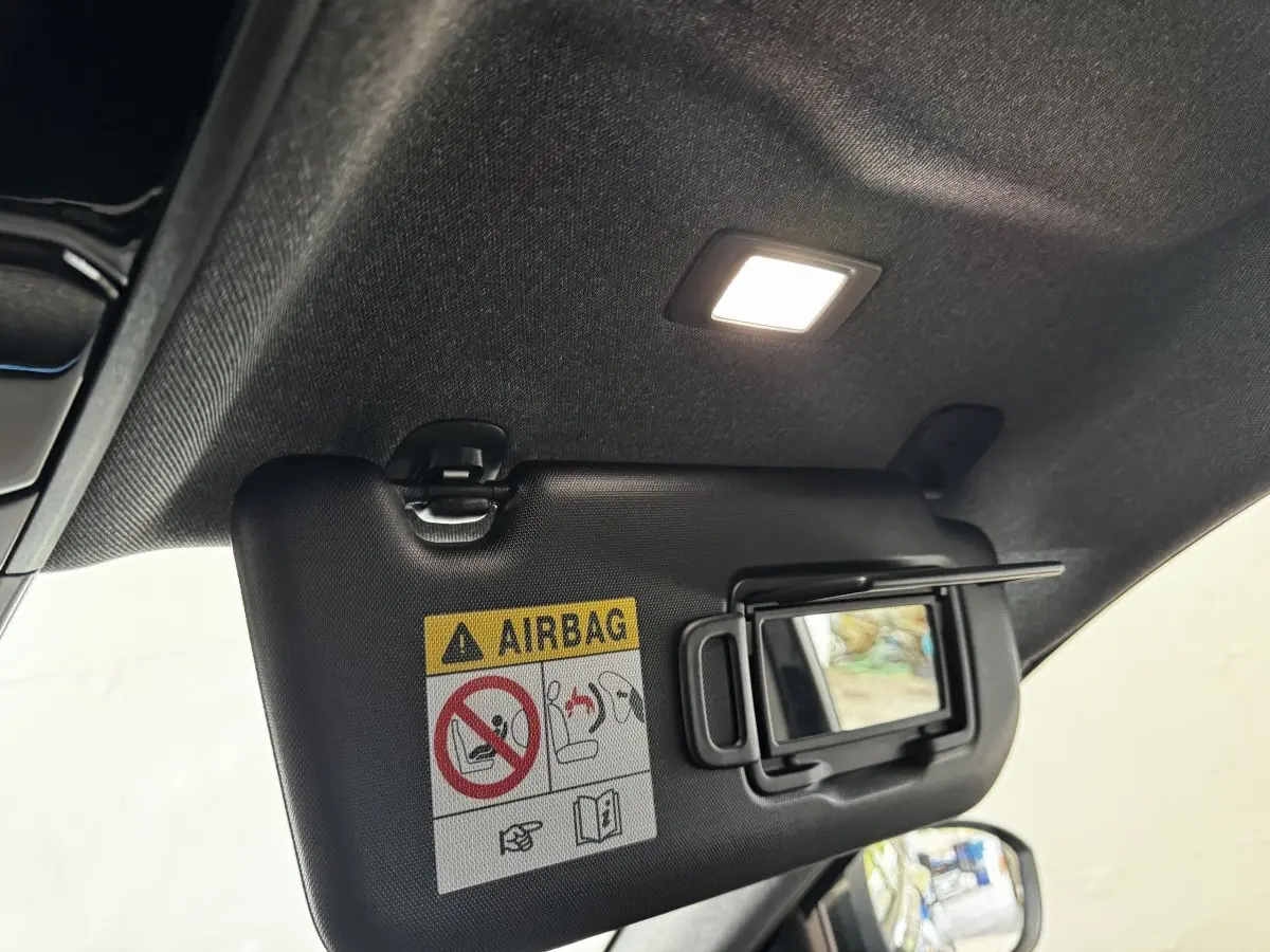 Détail intérieur du pare-soleil côté conducteur avec miroir et avertissement airbag, éclairage intérieur allumé, Renault Espace noir.