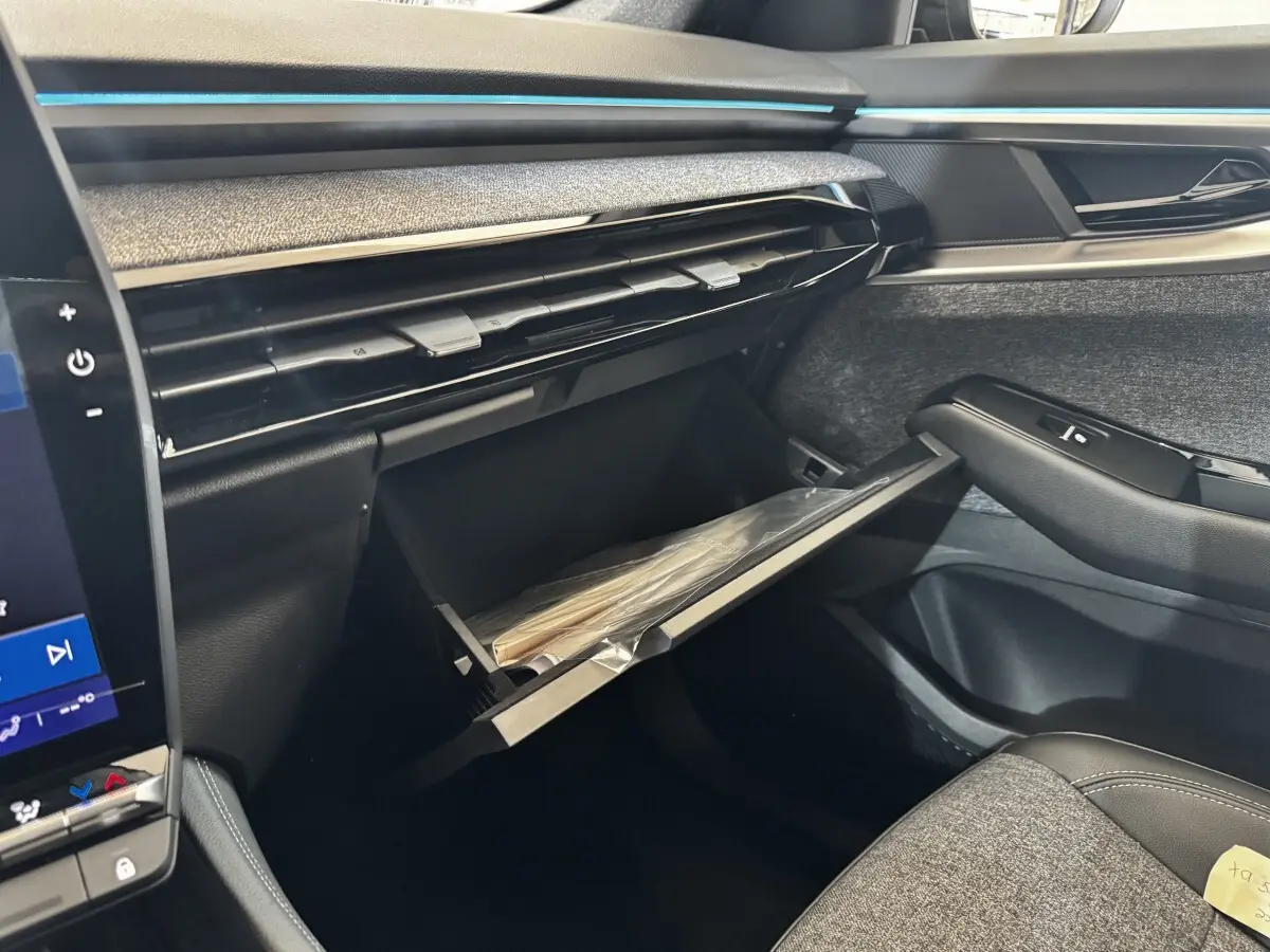Intérieur côté passager du Renault Espace 2025 noir, montrant la boîte à gants ouverte et la finition tissu et cuir.