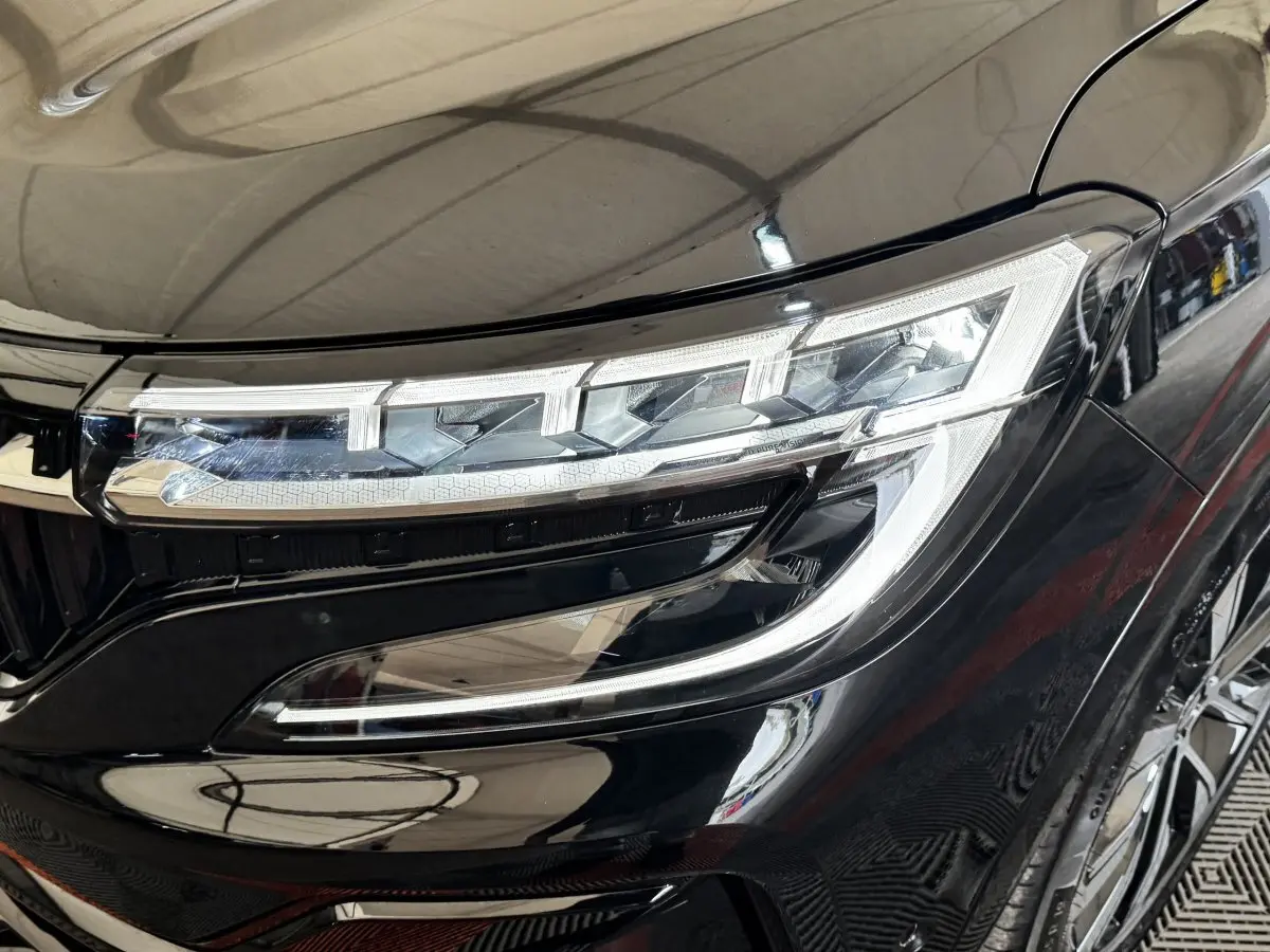 Gros plan sur le phare avant droit du Renault Espace noir 2025 avec détails LED et carrosserie brillante.