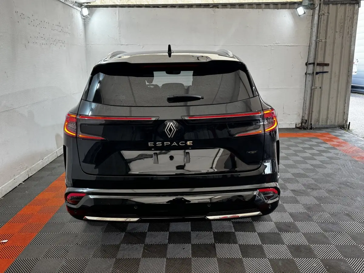 Vue arrière d'un Renault Espace noir 2025 avec feux LED allumés et rails de toit chromés dans un garage.